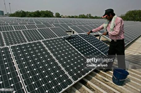 New Delhi, India – June 14, 2011: A solar panel is cleaned using a wet sponge. Solar power convets sunlight into electricity, Commercial concentrated solar power plants were first developed in the 1980s.