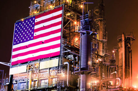 Night photograph of a huge industrial chemical plant and oil refinery installation in Southern California is adorned with a massive American flag.